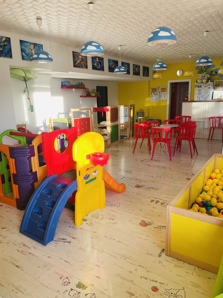 Priestor s hracím kútikom, žltými stenami a stolmi